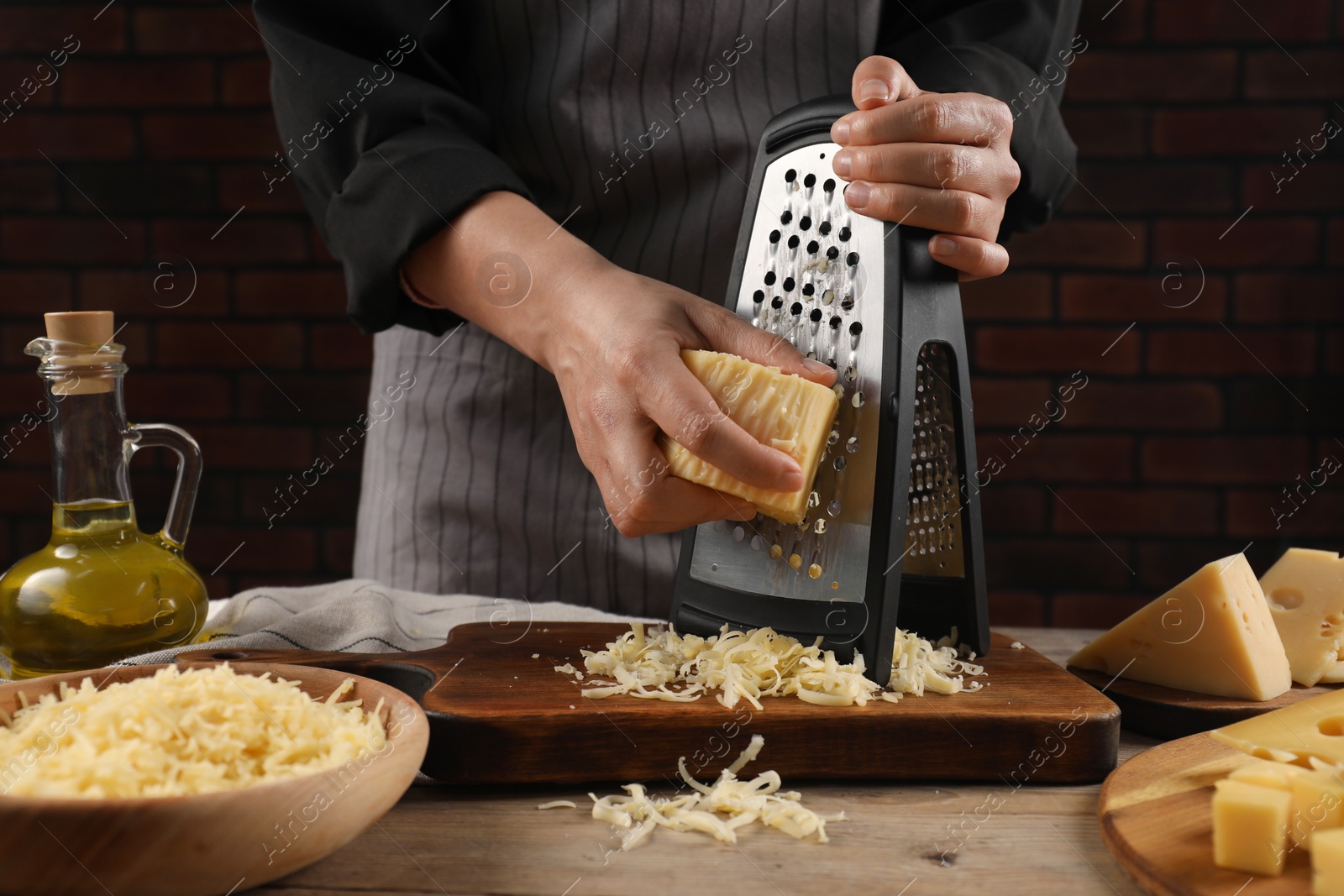 Photo of Woman grating cheese at wooden table, closeup