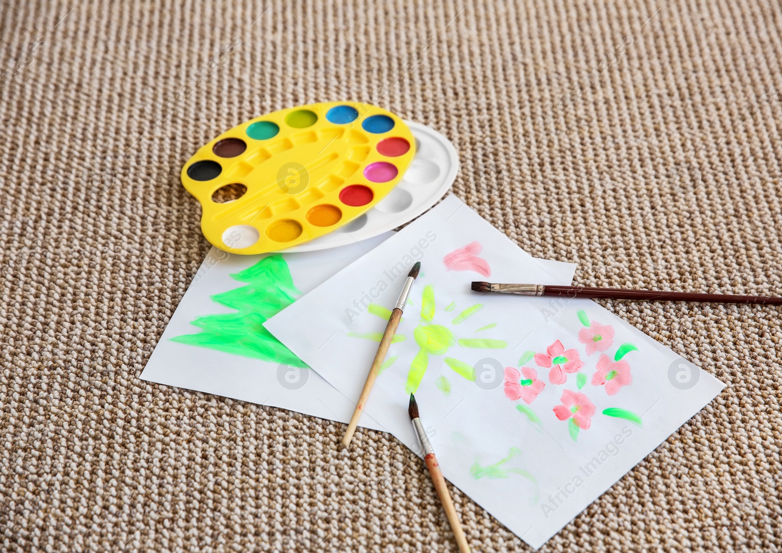 Photo of Paintings with palette and brushes on carpet