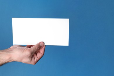 Photo of Man holding flyer on blue background, closeup. Mockup for design