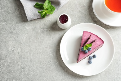 Photo of Flat lay composition with piece of tasty blueberry cake and space for text on gray table