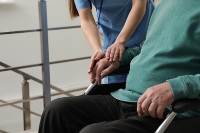 Photo of Nurse assisting senior man in wheelchair at hospital, closeup