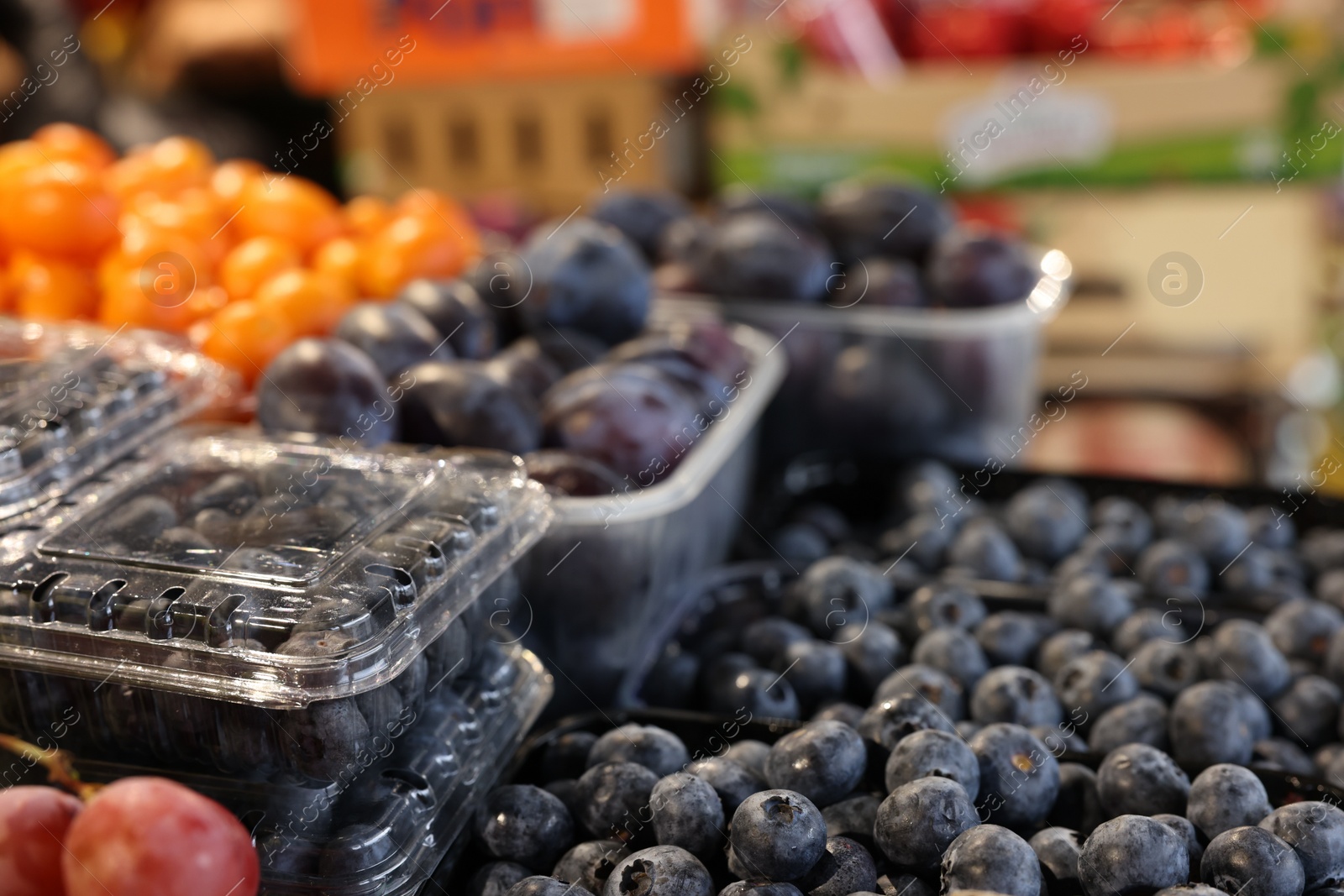 Photo of Fresh blueberries and plums on counter at market, closeup