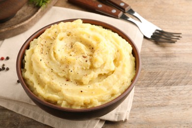 Photo of Bowl of tasty mashed potatoes with black pepper served on wooden table