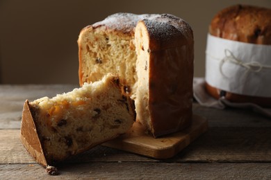 Delicious cut Panettone cake with raisins on wooden table. Traditional Italian pastry