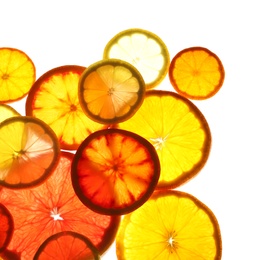 Illuminated slices of citrus fruits on white background, top view