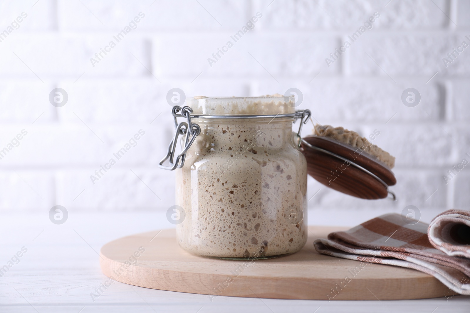 Photo of Sourdough starter in glass jar on white wooden table