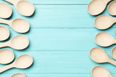 New wooden spoons on light blue wooden table, flat lay with space for text. Cooking utensils