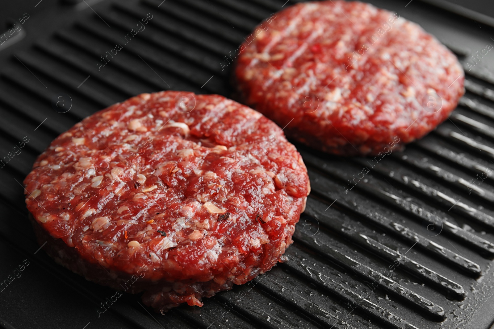 Photo of Raw meat cutlets for burger on grill, closeup