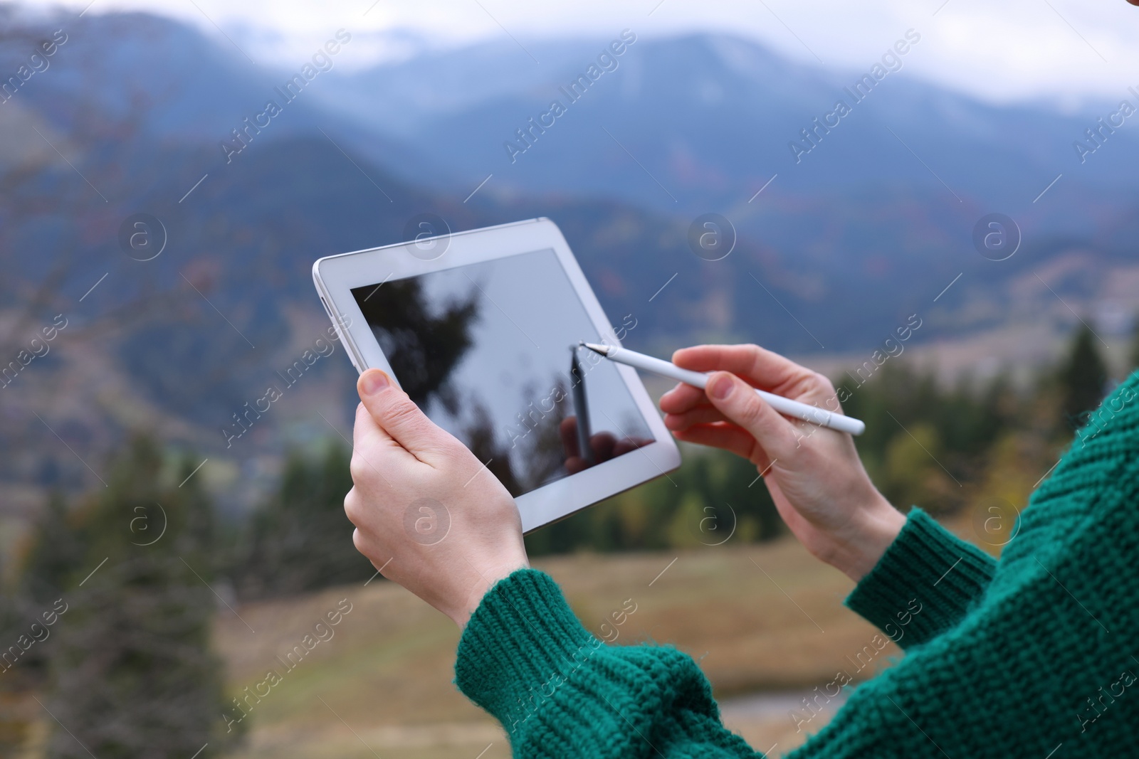 Photo of Young woman drawing on tablet in mountains, closeup