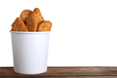 Photo of Bucket with tasty chicken nuggets on wooden table against white background. Space for text