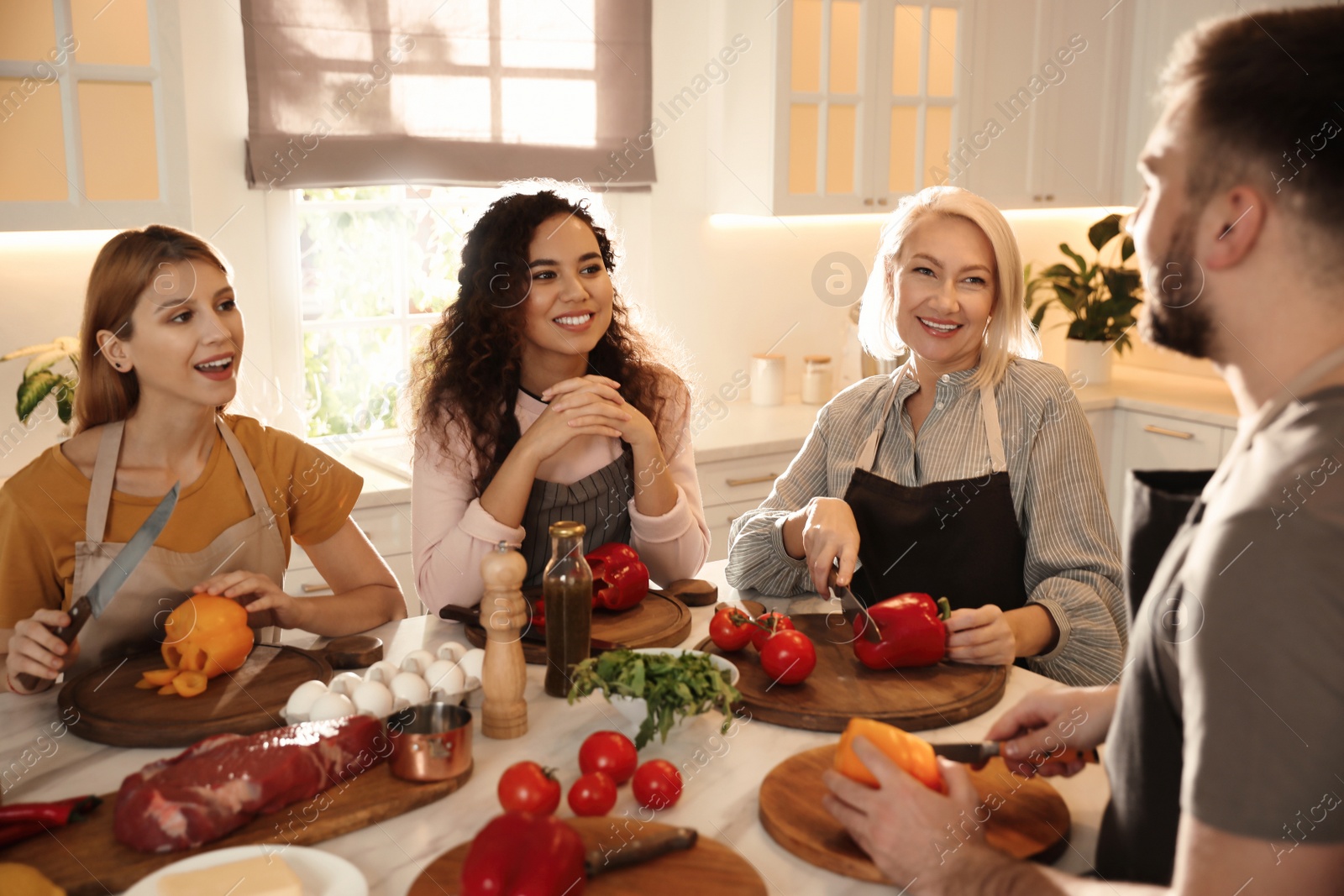 Photo of Happy people cooking food together in kitchen