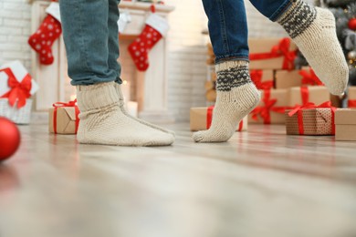 Image of Couple in warm socks in room decorated for Christmas, closeup