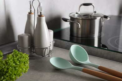 Photo of Set of different cooking utensils on grey countertop in kitchen