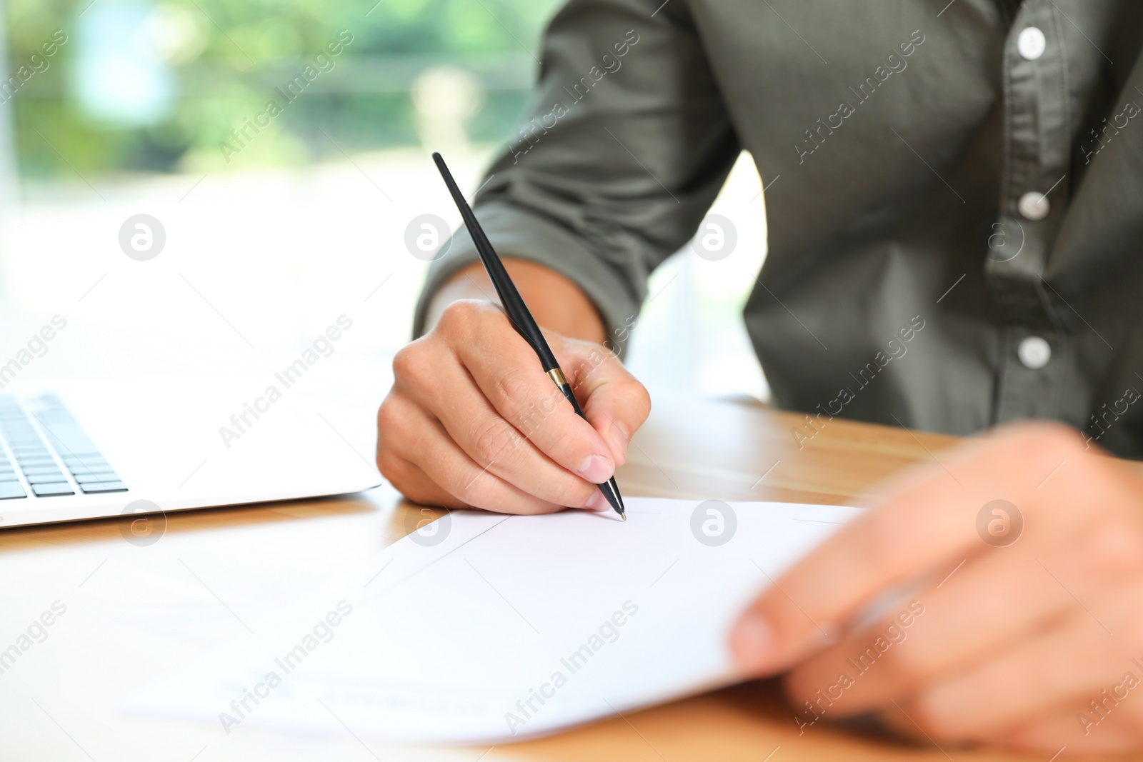 Photo of Male notary signing document at table in office, closeup