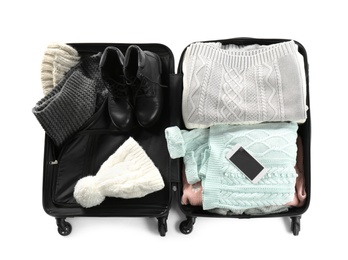 Packed suitcase with warm clothes and smartphone on white background, top view. Space for text