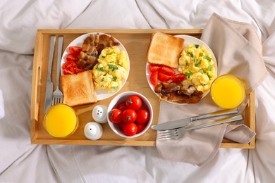 Photo of Good morning. Tray with tasty breakfast on bed, top view