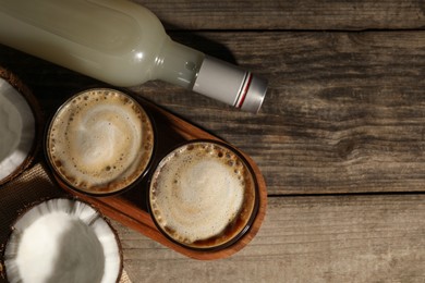 Glasses of tasty coffee with coconut syrup on wooden table, flat lay. Space for text