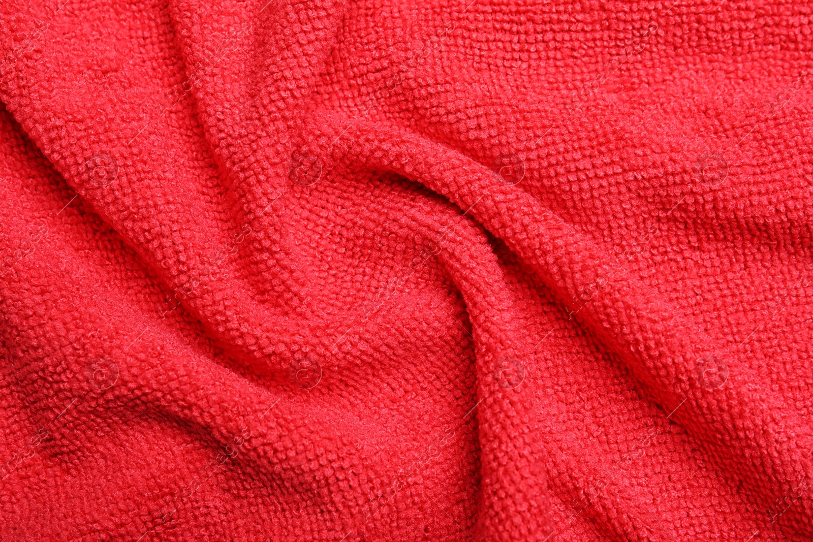 Photo of Crumpled red microfiber cloth as background, closeup