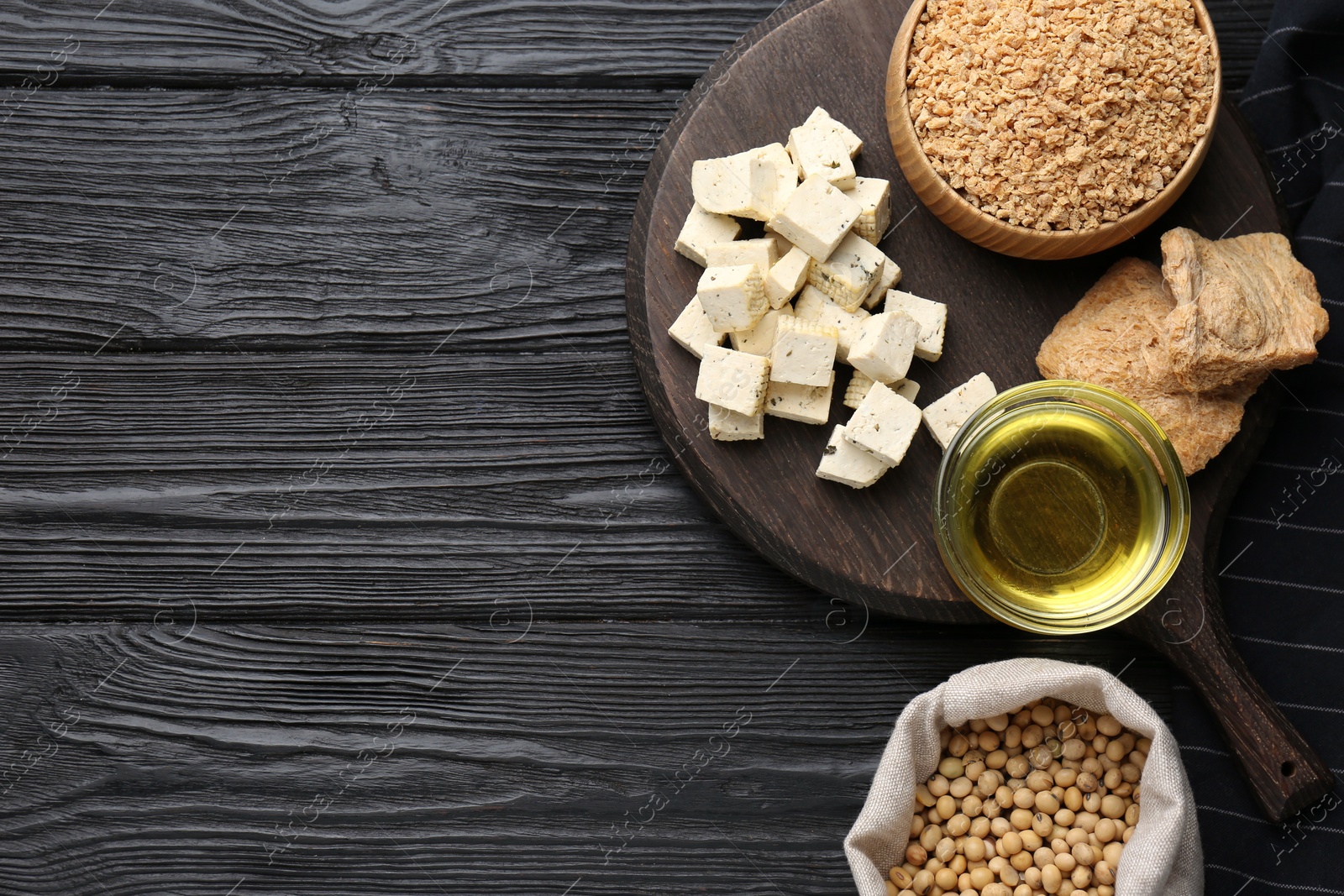 Photo of Different natural soy products on black wooden table, flat lay. Space for text