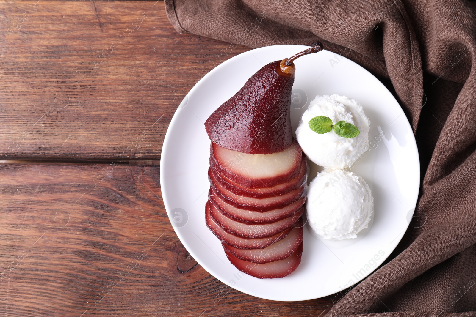 Photo of Tasty red wine poached pear and ice cream on wooden table, top view. Space for text
