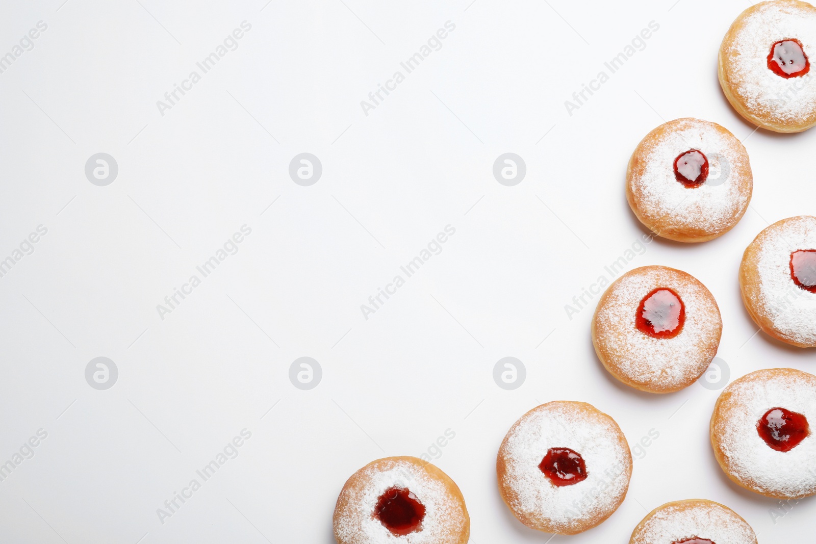 Photo of Hanukkah doughnuts with jelly and sugar powder on white background, top view. Space for text