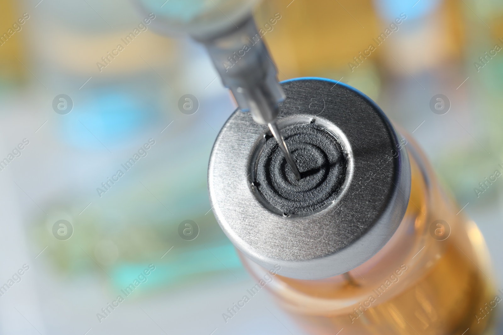 Photo of Filling syringe with orange medication from glass vial against blurred background, closeup. Space for text