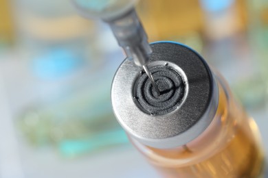 Filling syringe with orange medication from glass vial against blurred background, closeup. Space for text