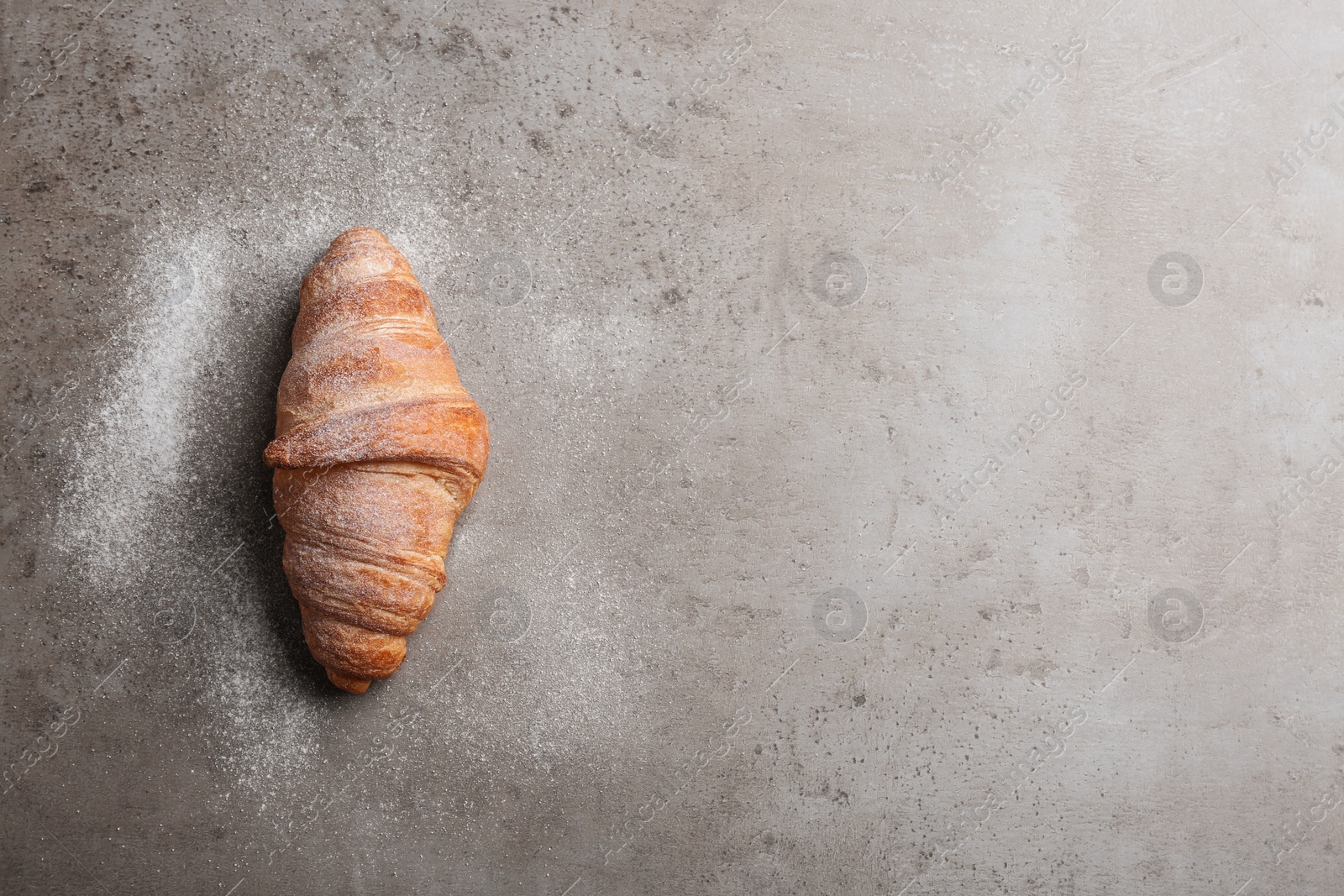 Photo of Tasty croissant with powdered sugar and space for text on grey background, top view. French pastry