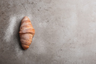 Photo of Tasty croissant with powdered sugar and space for text on grey background, top view. French pastry