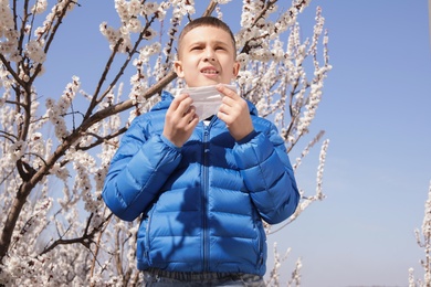 Little boy suffering from seasonal allergy outdoors on sunny day