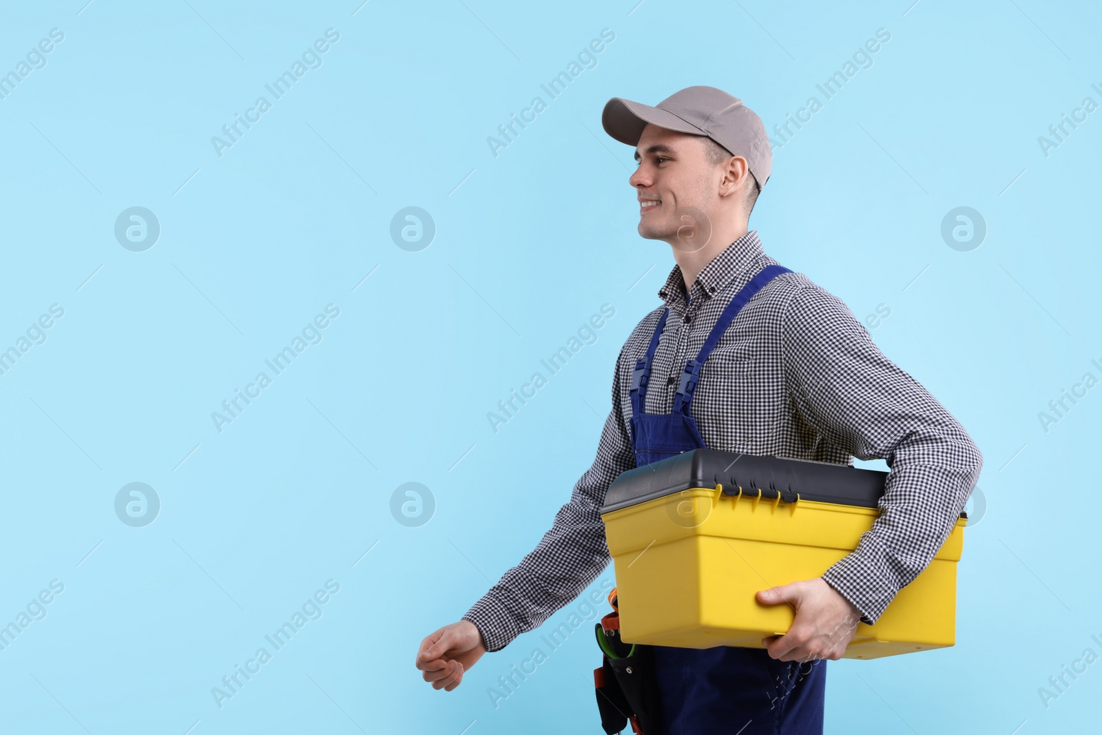 Photo of Professional repairman with tool box on light blue background. Space for text