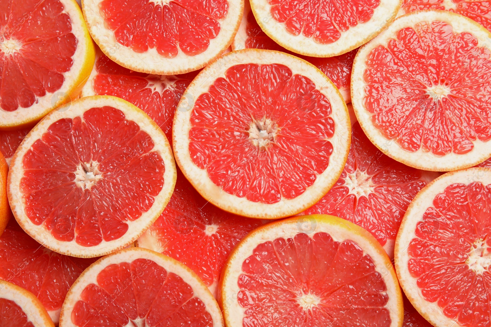 Photo of Many sliced fresh grapefruits as background, top view