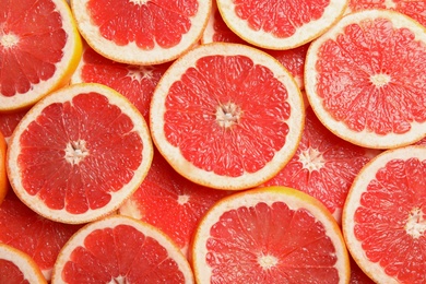 Many sliced fresh grapefruits as background, top view