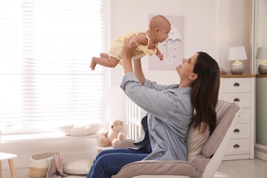 Happy young mother with her cute baby in armchair at home