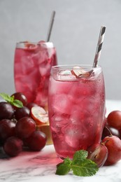Photo of Delicious grape soda water with mint and berries on white marble table. Refreshing drink