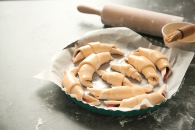 Photo of Baking dish with raw croissants on table