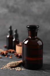 Photo of Bottles of anise essential oil and seeds on black table