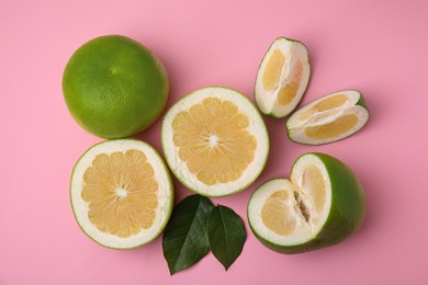 Whole and cut sweetie fruits with green leaves on pink background, flat lay