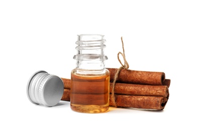 Photo of Bottle of cinnamon oil and sticks on white background