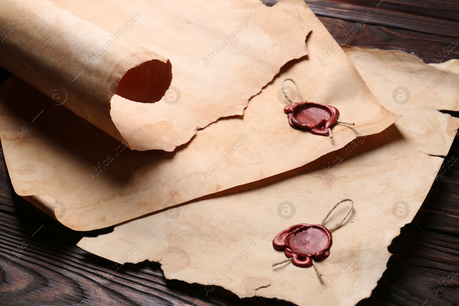 Photo of Sheets of old parchment paper with wax stamps on wooden table