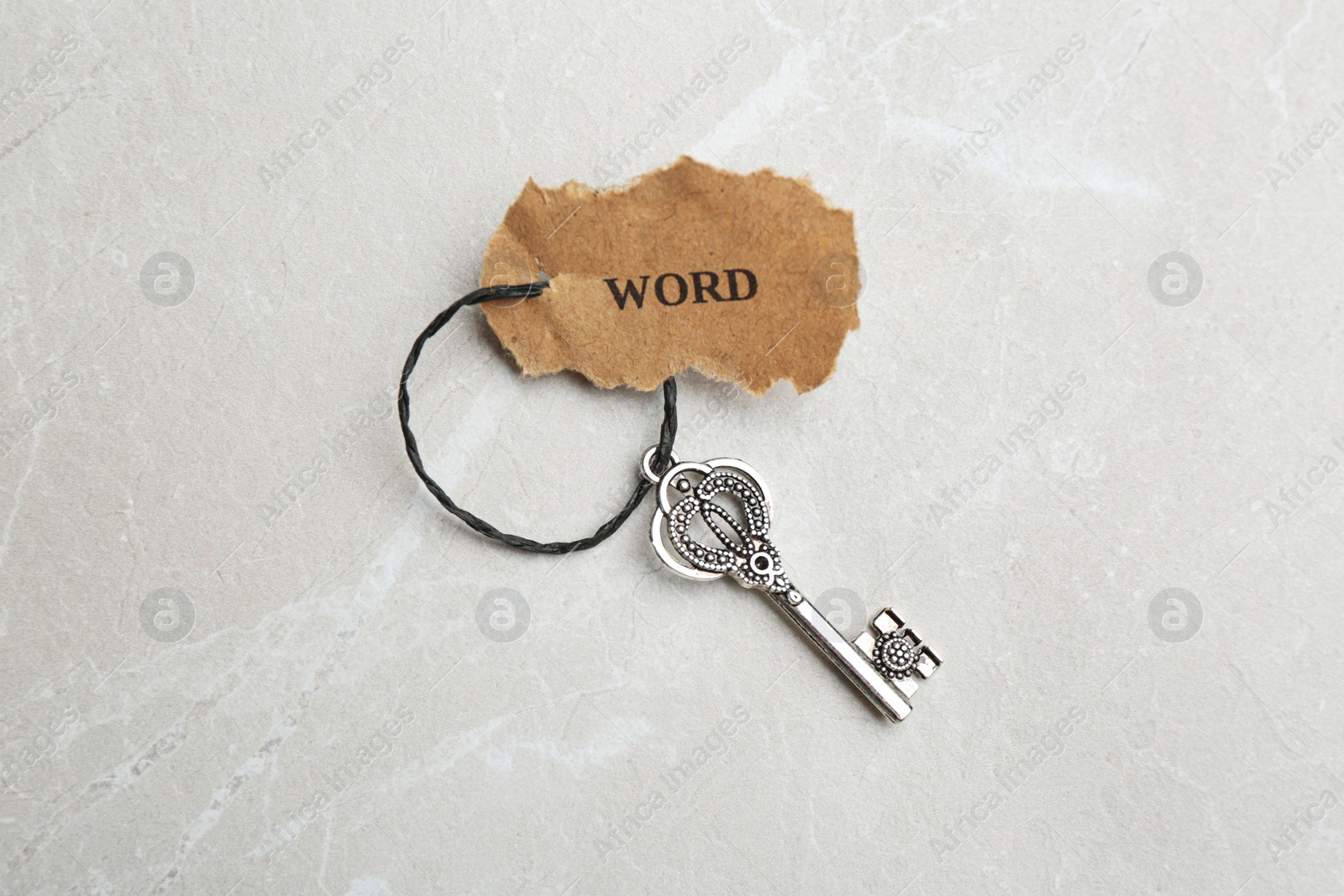 Photo of Vintage key with tag on light grey table, top view. Keyword concept