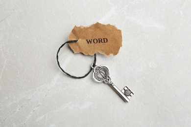 Photo of Vintage key with tag on light grey table, top view. Keyword concept