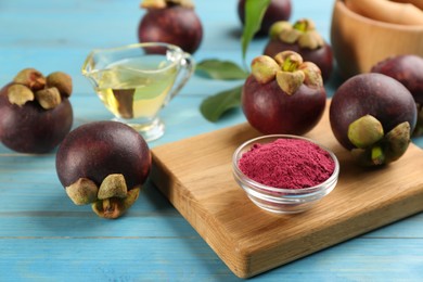 Purple mangosteen powder and fruits on light blue wooden table