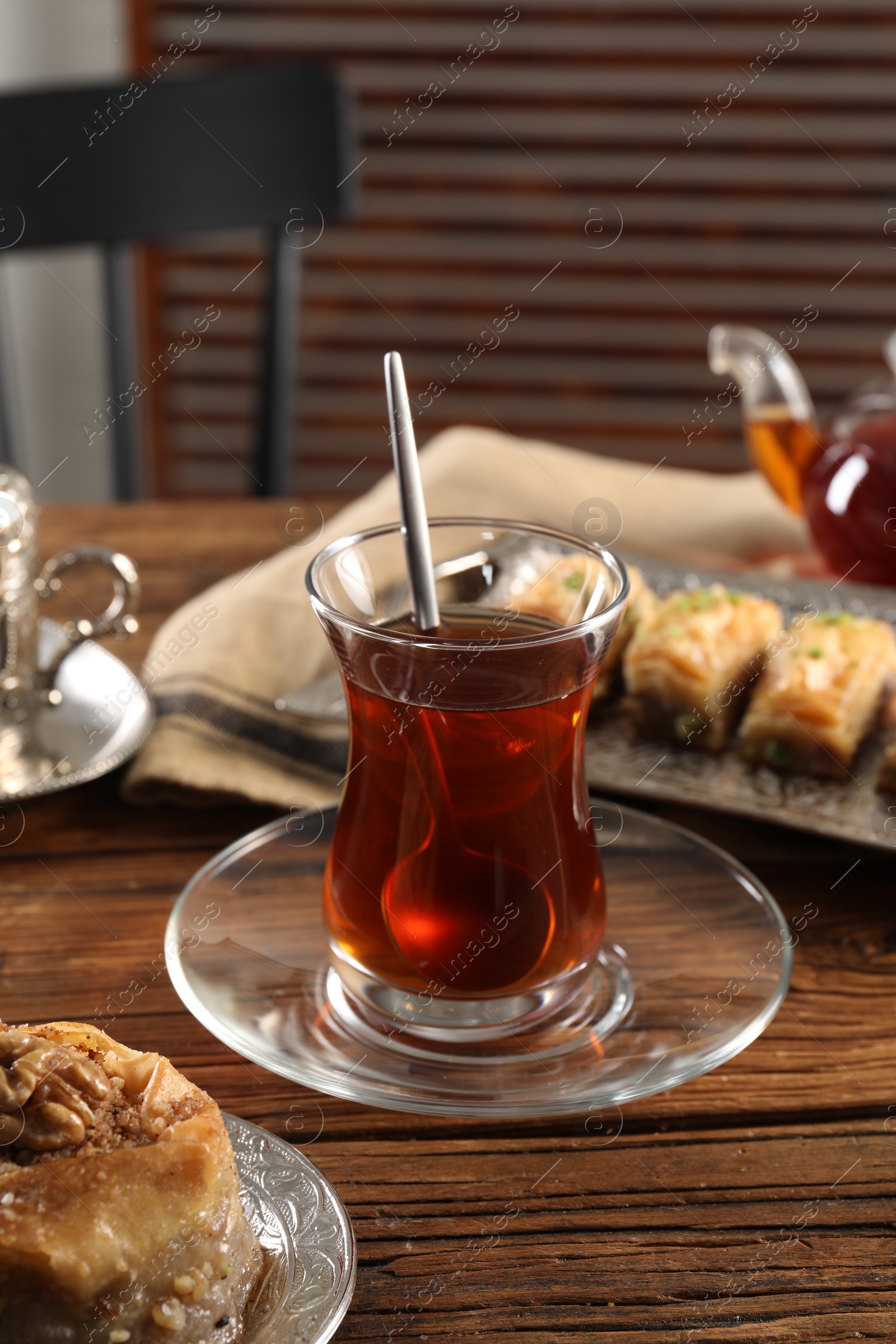 Photo of Traditional Turkish tea in glass and fresh baklava on wooden table