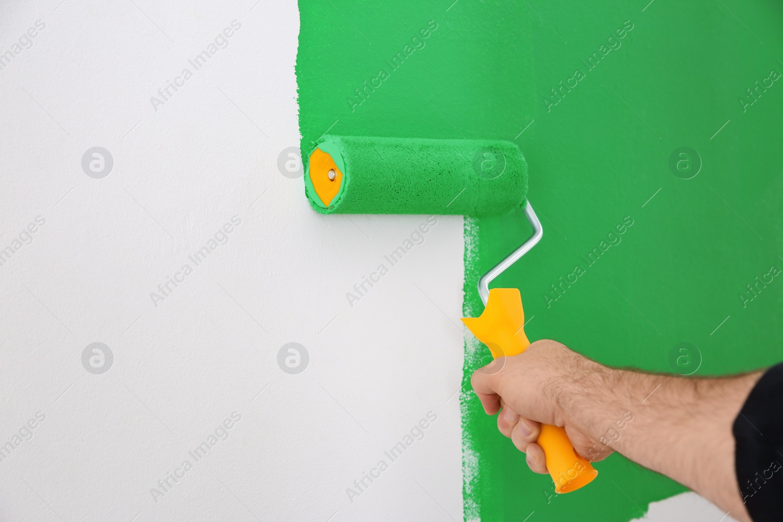 Photo of Man painting white wall with green dye, closeup. Interior renovation