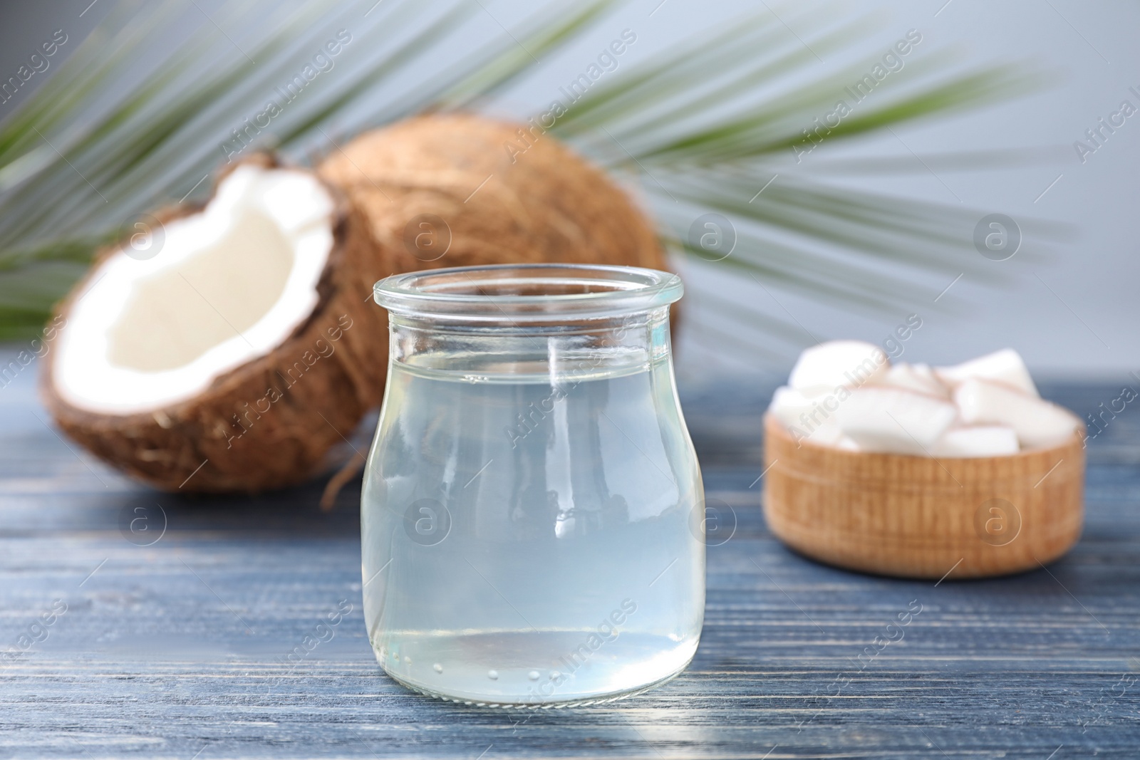 Photo of Coconut oil on blue wooden table, closeup view