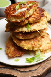 Stack of tasty parsnip cutlets with green onion on wooden board, closeup