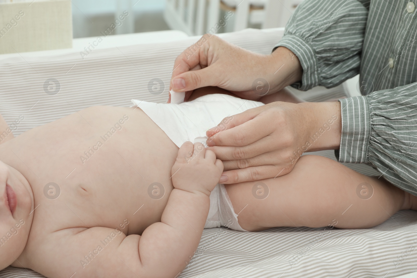 Photo of Mother changing baby's diaper on table at home, closeup