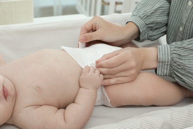 Mother changing baby's diaper on table at home, closeup