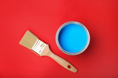 Photo of Flat lay composition with paint can and brush on red background